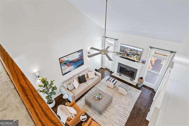 living room with lofted ceiling, ceiling fan, and dark wood-type flooring