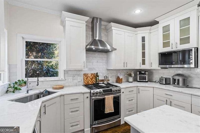 kitchen featuring appliances with stainless steel finishes, wall chimney range hood, and white cabinetry