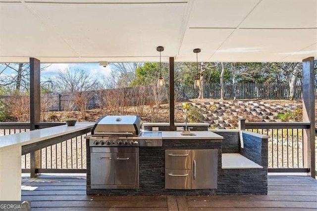 wooden deck featuring an outdoor kitchen, sink, and a grill