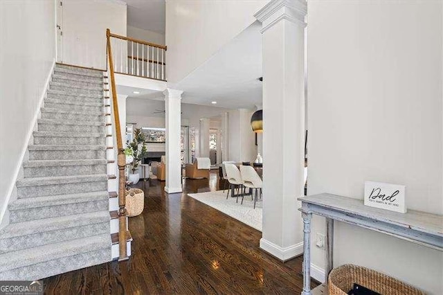 foyer entrance with ornate columns and dark hardwood / wood-style flooring