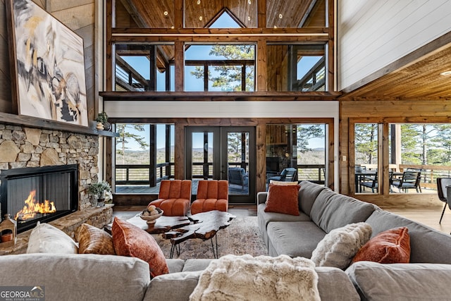 living room featuring a wealth of natural light, wooden ceiling, and a fireplace