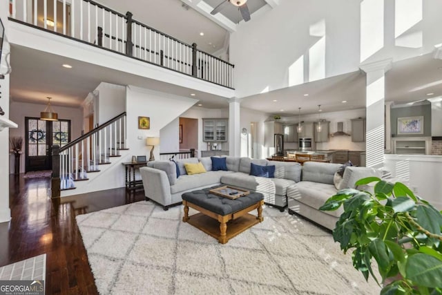 living room with ceiling fan, hardwood / wood-style flooring, a high ceiling, and decorative columns