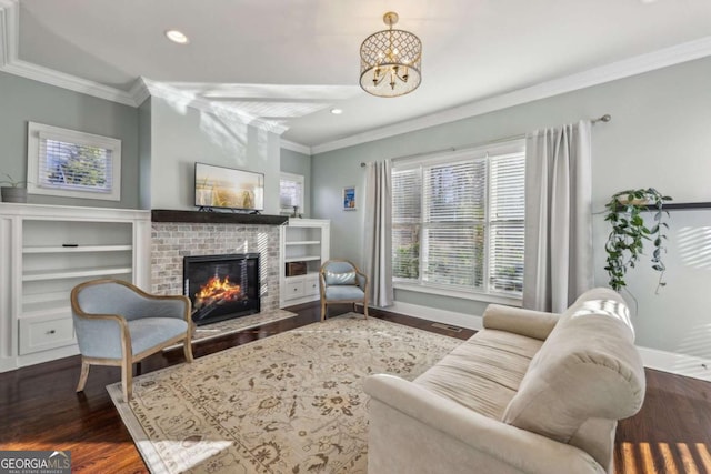 living room featuring a brick fireplace, dark wood-type flooring, crown molding, and a chandelier