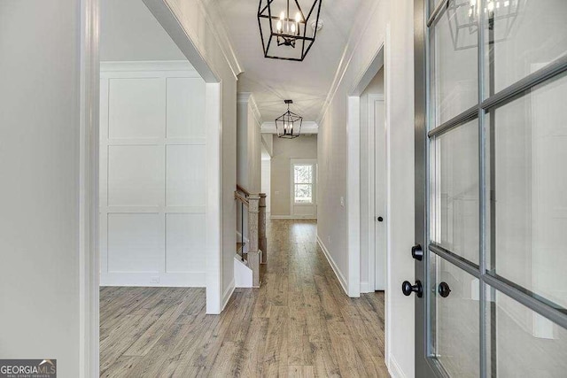 hall featuring a chandelier, crown molding, and light hardwood / wood-style floors