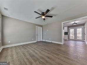 spare room featuring dark wood-type flooring, ceiling fan, and french doors