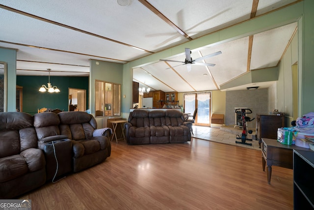 living room featuring hardwood / wood-style flooring, ceiling fan with notable chandelier, and vaulted ceiling with beams