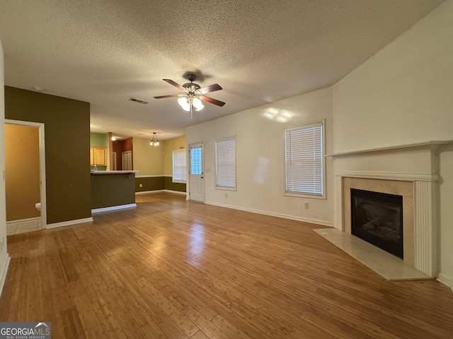 unfurnished living room with ceiling fan, a high end fireplace, hardwood / wood-style floors, and a textured ceiling