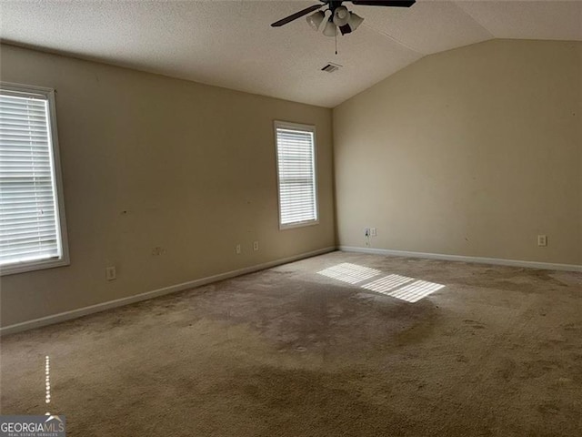 carpeted spare room with ceiling fan, vaulted ceiling, and a textured ceiling