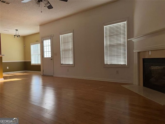 unfurnished living room with wood-type flooring, ceiling fan, and a textured ceiling