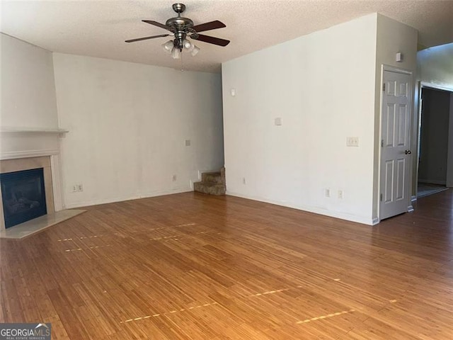 unfurnished living room featuring ceiling fan, wood-type flooring, and a textured ceiling