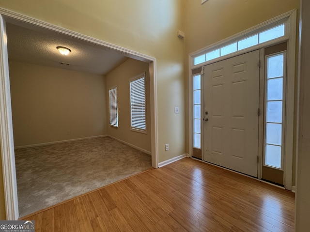 foyer entrance with a textured ceiling and light hardwood / wood-style flooring