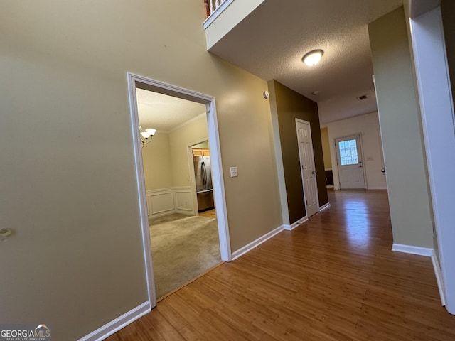 hall with wood-type flooring and a textured ceiling