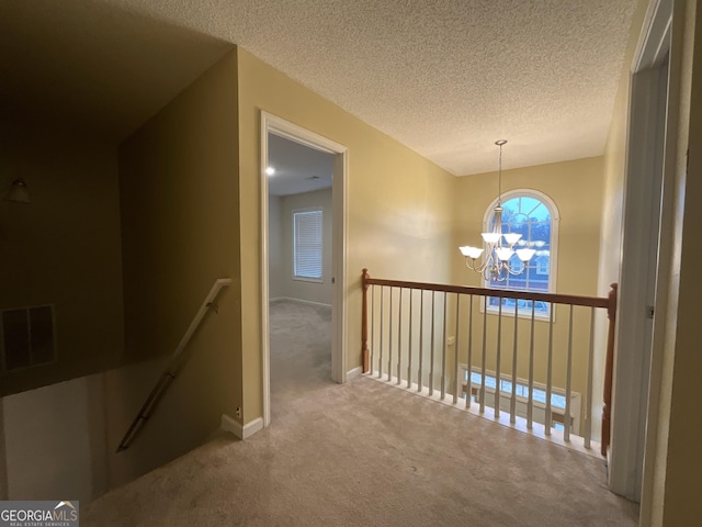 corridor with an inviting chandelier, carpet, and a textured ceiling