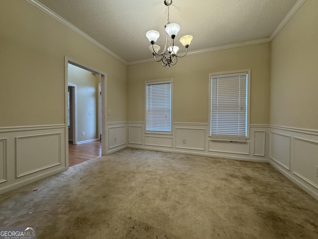 carpeted empty room featuring ornamental molding, a textured ceiling, and a notable chandelier