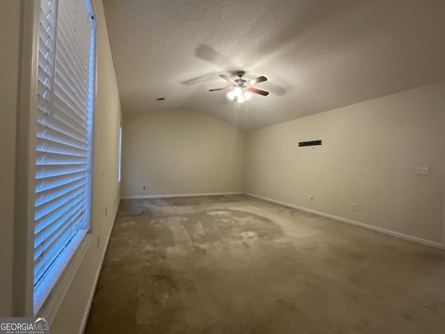 carpeted spare room featuring lofted ceiling, ceiling fan, and a textured ceiling