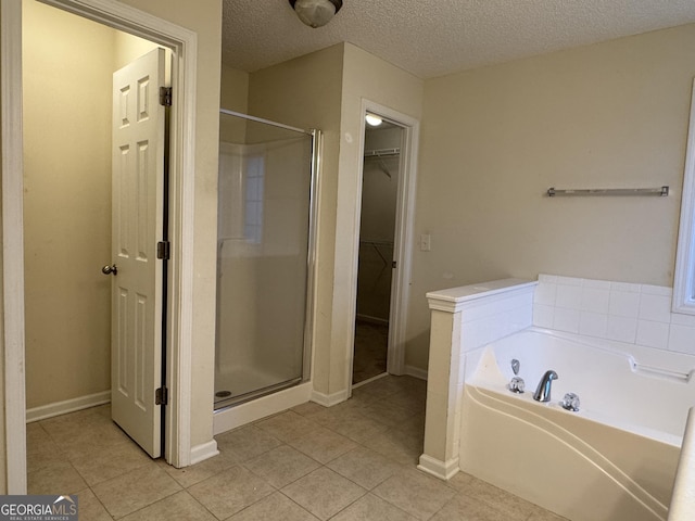 bathroom with tile patterned floors, plus walk in shower, and a textured ceiling