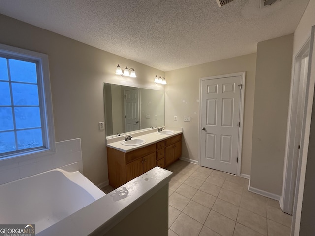 bathroom featuring tile patterned floors, a bath, a textured ceiling, and vanity