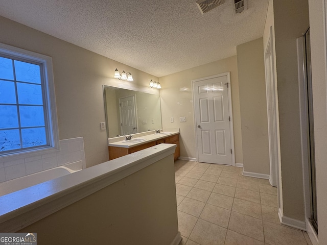 bathroom featuring tile patterned flooring, vanity, a bathing tub, and a textured ceiling