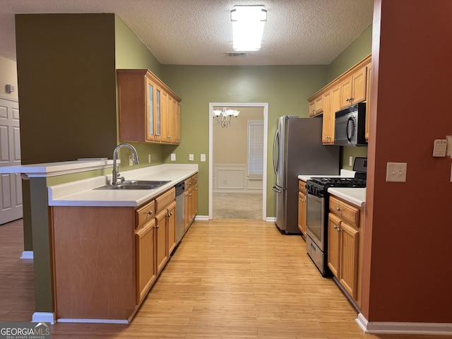 kitchen with sink, a chandelier, light hardwood / wood-style floors, stainless steel appliances, and a textured ceiling