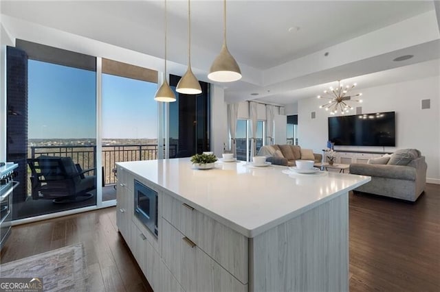 kitchen featuring stainless steel microwave, decorative light fixtures, dark hardwood / wood-style floors, a notable chandelier, and a kitchen island