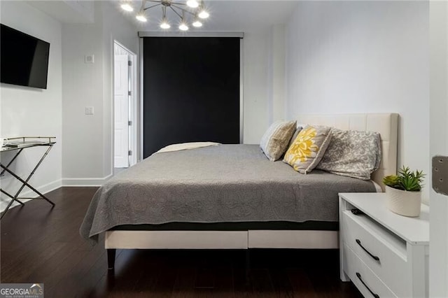 bedroom with dark hardwood / wood-style floors and a notable chandelier