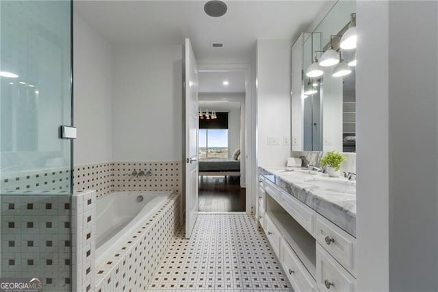 bathroom featuring tiled tub and vanity