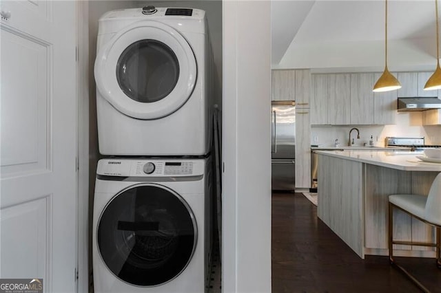 laundry room featuring sink, dark hardwood / wood-style floors, and stacked washer and clothes dryer