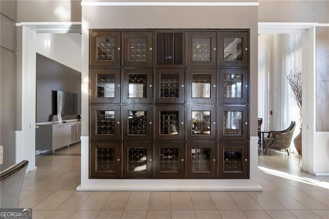 bar with light tile patterned floors and dark brown cabinets