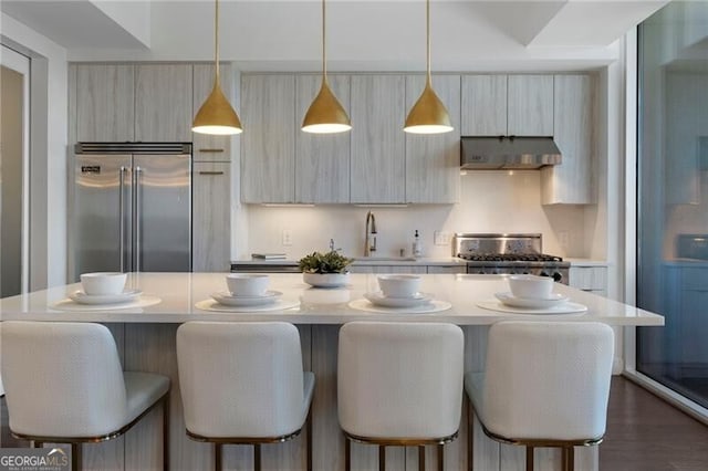 kitchen featuring stainless steel built in fridge, a center island, decorative light fixtures, stove, and sink