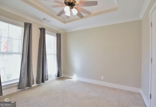 spare room with ceiling fan, plenty of natural light, a raised ceiling, and light carpet