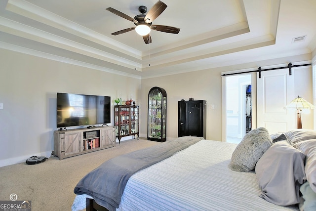 bedroom with carpet floors, ceiling fan, a raised ceiling, crown molding, and a barn door