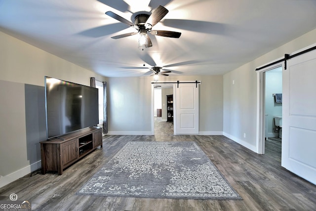 unfurnished living room featuring dark hardwood / wood-style floors, ceiling fan, and a barn door