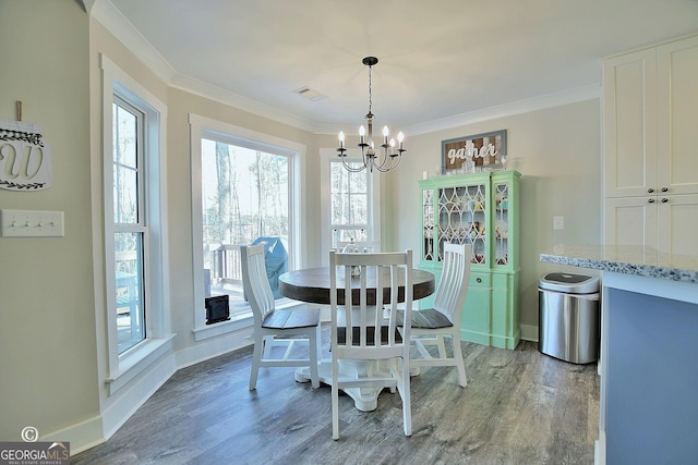 dining area with an inviting chandelier, crown molding, and wood-type flooring