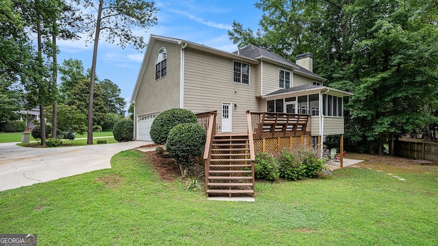 rear view of house with a deck, a garage, a yard, and a sunroom