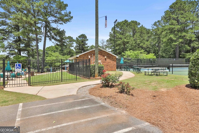 view of home's community with tennis court and a yard