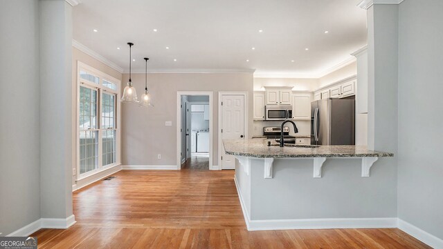 kitchen featuring white cabinetry, appliances with stainless steel finishes, backsplash, decorative light fixtures, and light stone countertops