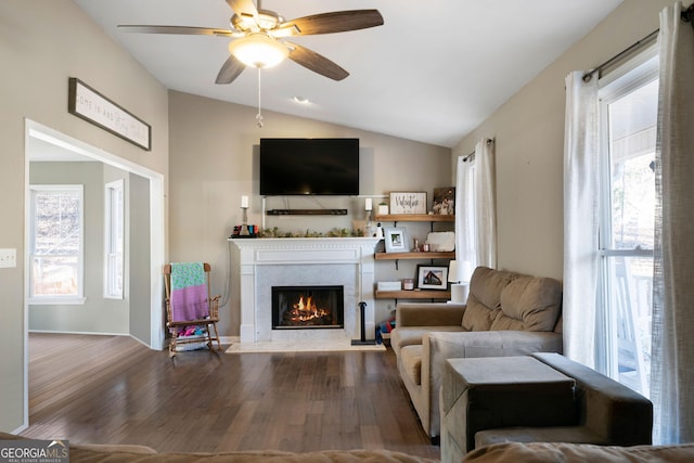 living room featuring a ceiling fan, lofted ceiling, wood finished floors, and a high end fireplace