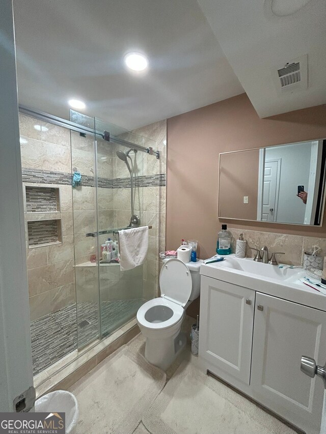 bathroom with toilet, a shower with shower door, and vanity