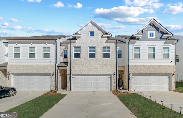 townhome / multi-family property with driveway, brick siding, and an attached garage