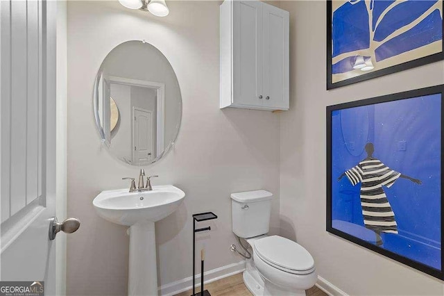 half bathroom with baseboards and toilet