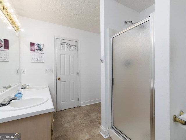 bathroom featuring a textured ceiling, a shower with door, and vanity