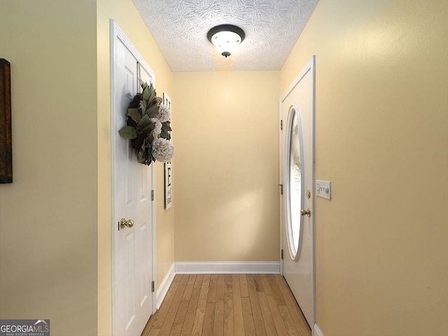 doorway with a textured ceiling and light hardwood / wood-style floors