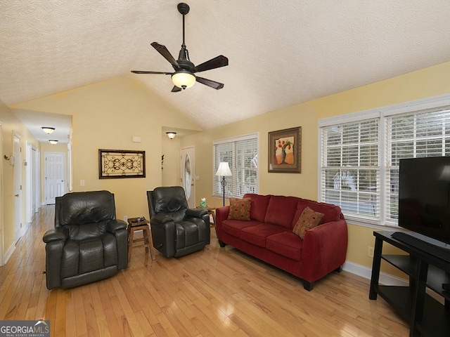 living room featuring a wealth of natural light, a textured ceiling, lofted ceiling, ceiling fan, and light hardwood / wood-style flooring