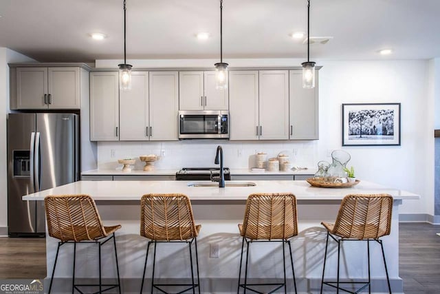 kitchen with an island with sink, stainless steel appliances, and pendant lighting