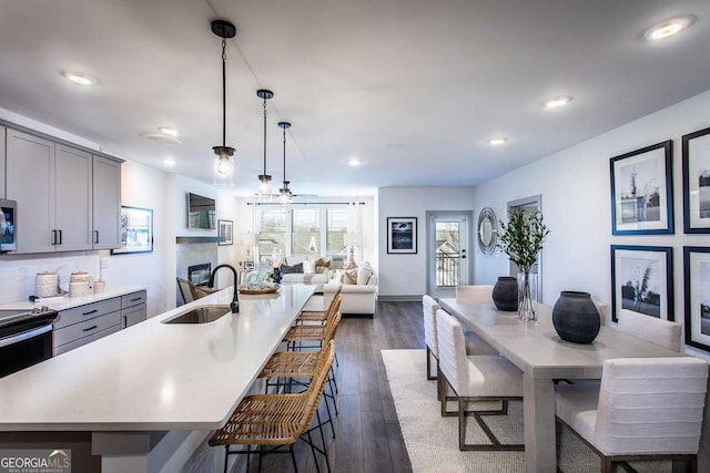 kitchen with dark wood-type flooring, gray cabinets, pendant lighting, and sink