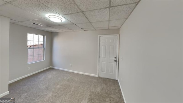 empty room with a drop ceiling and carpet flooring