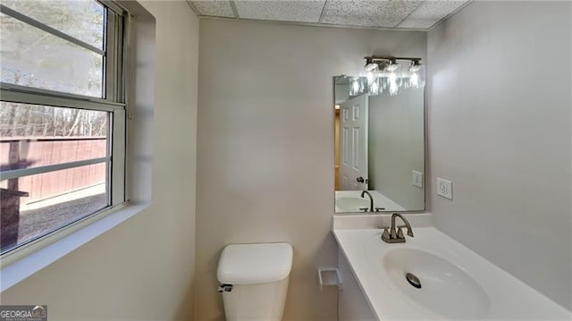 bathroom with a drop ceiling, toilet, and vanity