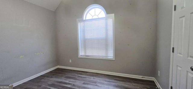 empty room with vaulted ceiling and dark wood-type flooring