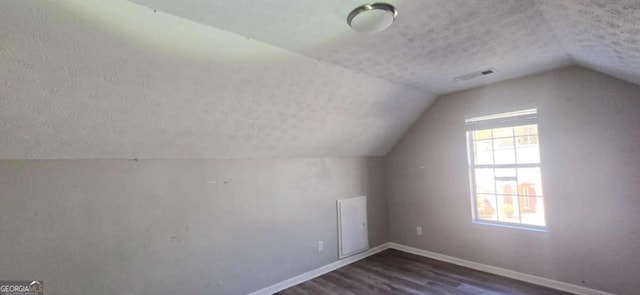 bonus room with a textured ceiling, dark hardwood / wood-style flooring, and vaulted ceiling