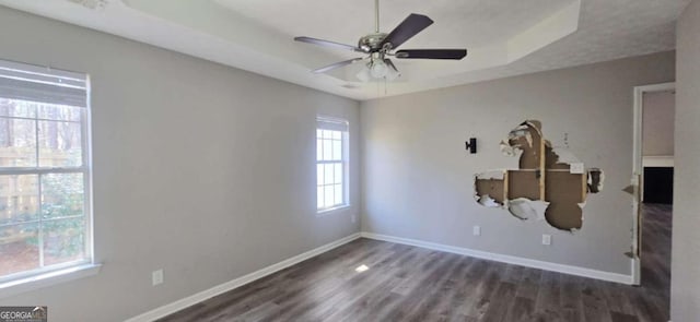 unfurnished room with ceiling fan, dark hardwood / wood-style flooring, and a raised ceiling